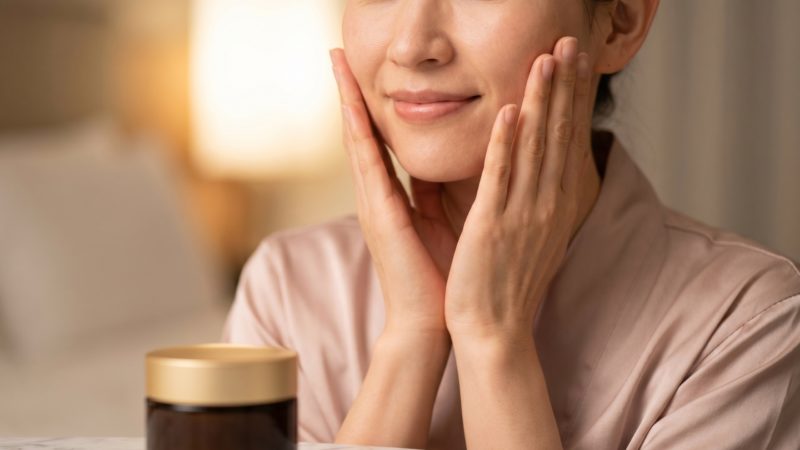 就寝前のスキンケアで、高保湿なオールインワンジェルを使用した後の肌の感触を確かめる女性。