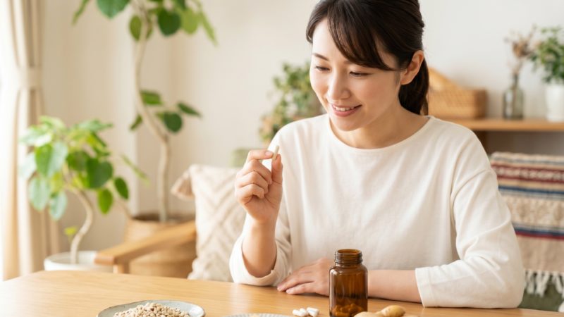 おすすめのサプリメント成分を確認しながら、日々のむくみ悩みを解消するためにカプセルを飲もうとする女性。