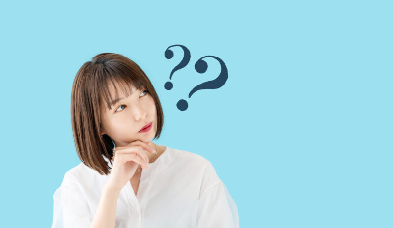 自分に合ったコラーゲンドリンクの選び方に迷い、人差し指を顎に当てて考え込む女性。