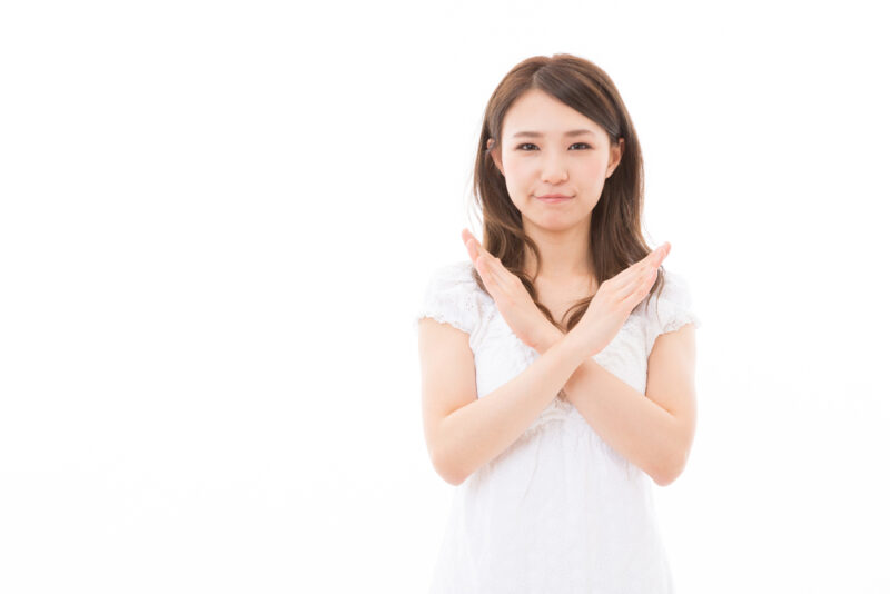 防風通聖散の服用時の注意点や禁止事項を、腕でバツ印を作って表現する女性の様子。