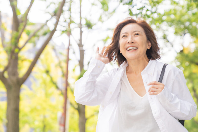 新緑の公園を散策し、明るい笑顔を見せる活動的で健康的な50代の女性。