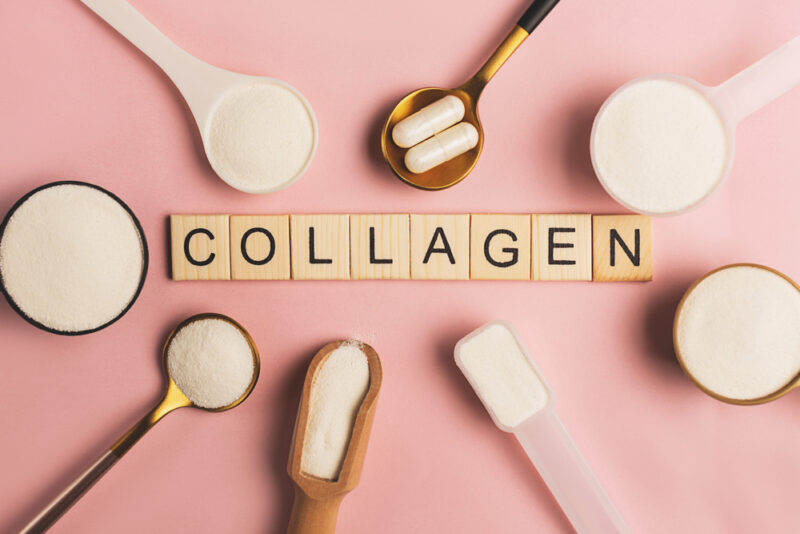 サプリやドリンクの主役であるコラーゲンの粉末・カプセル。中央に「COLLAGEN」の文字が配置された、ピンク基調の素材イメージ。