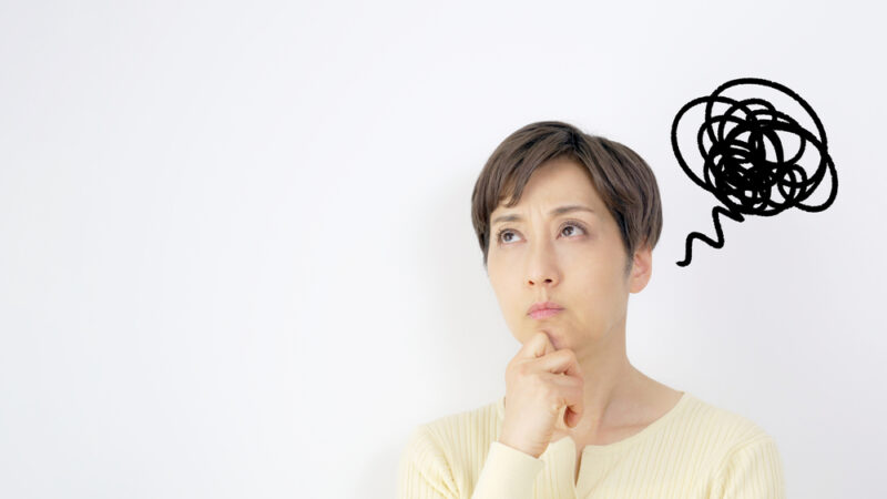 解消されない体や心の不調に不安を感じ、考え事をしている悩める表情の女性。