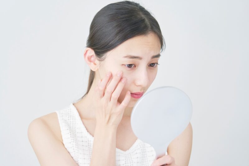 自身の肌質を確認し、毛穴や乾燥対策を検討する女性。現在の肌タイプを把握して、最適なセラミドサプリメントを選ぶためのセルフチェック。