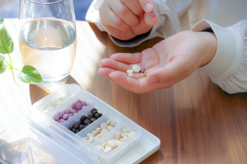 毎日継続して服用するために、数種類の防風通聖散の錠剤を手に取り、飲み込もうとする様子。