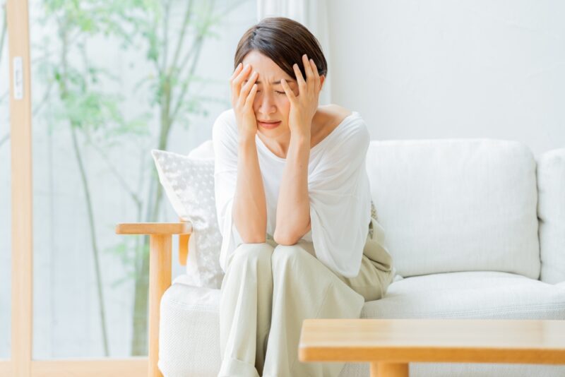 女性ホルモンの減少に伴うメンタルバランスの乱れにより、家で一人悩み込む女性。