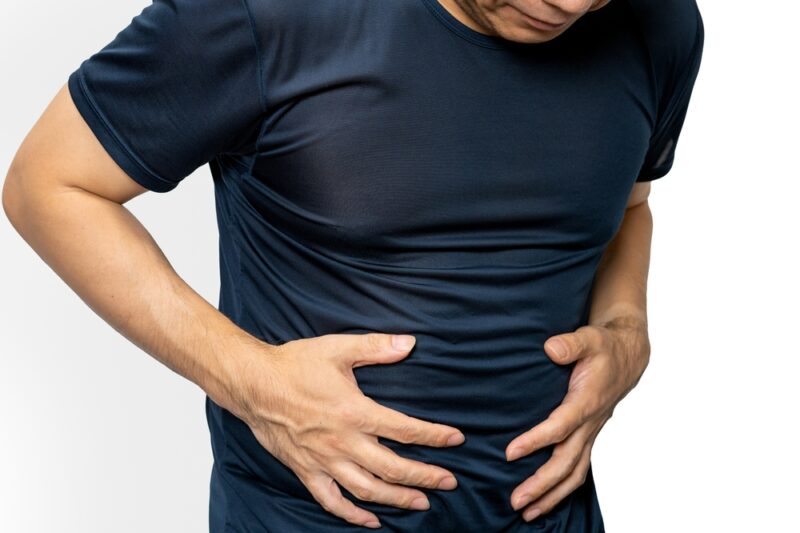 内臓脂肪の蓄積による体型の変化を気にして、自身のお腹の状態をチェックしている男性の様子。