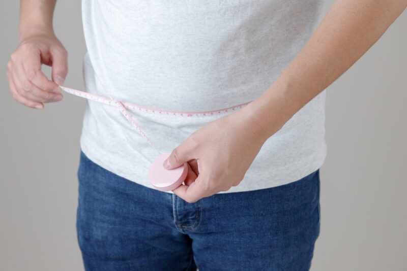 効率よく痩せるために、メタボリックシンドロームの指標となる腹囲をメジャーで測定している男性。