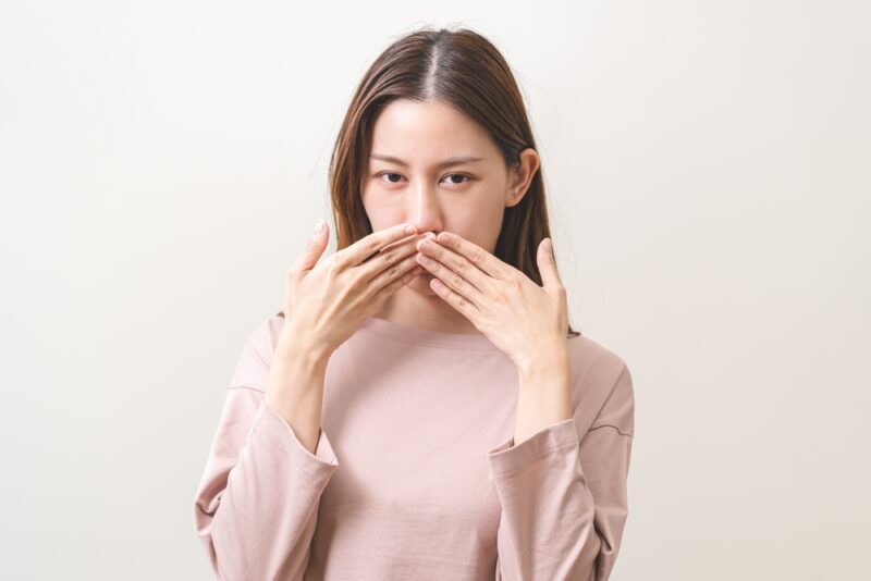 にんにくサプリを飲む際に気になる臭いの悩み。口元を隠してチェックする女性の様子。