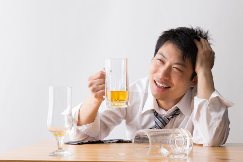 アルコール摂取による尿酸値への影響に悩む男性。飲み会の後の不安や健康管理のイメージ。