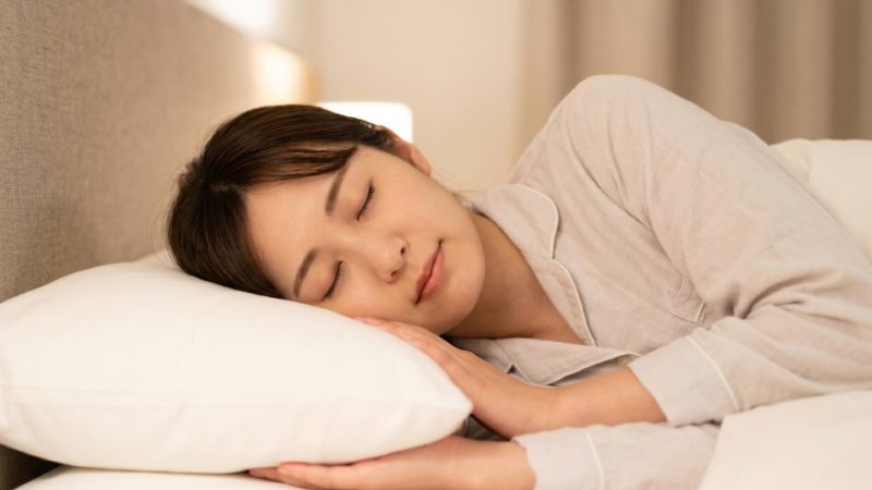 肌のターンオーバーを促して肌荒れを改善するために、ベッドで十分な睡眠をとりしっかりと休息する女性。