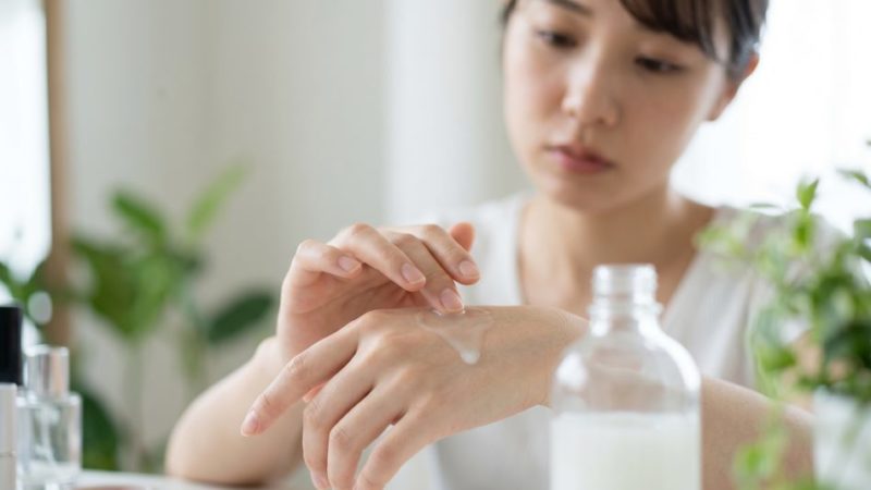 自分の肌荒れに合ったスキンケア用品を選ぶため、化粧水のテクスチャーを手の甲に出して確認する女性。