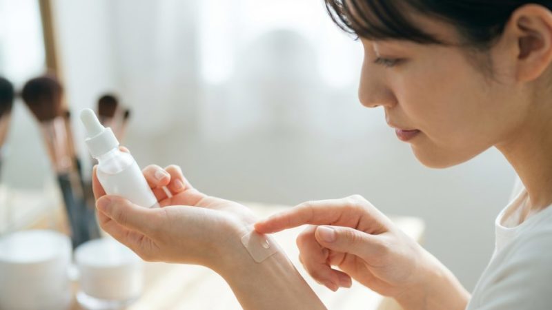 敏感肌の肌荒れやトラブルを防ぐため、新しい美容液を使用する前に手首でパッチテストを行う女性。