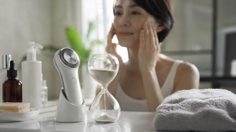 美顔器ケアの継続時間を意識する女性。砂時計を使いながら、短時間でも毎日コツコツと続けることが、たるみ改善への一番の近道。
