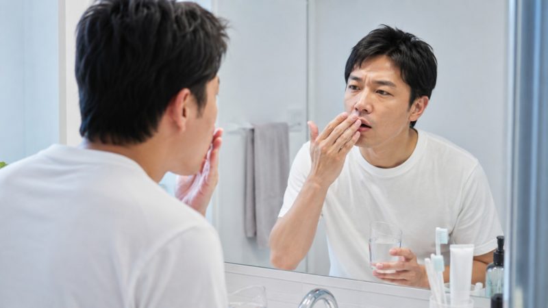 自宅で簡単にできる口臭をチェックする方法を実践し、自分の息の状態を確認する男性。