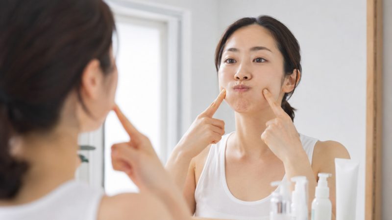 美顔器の効果を高めるための表情筋エクササイズ。鏡を見ながら頬の筋肉を意識的に動かし、内側からたるみをケアするホームケアの様子。