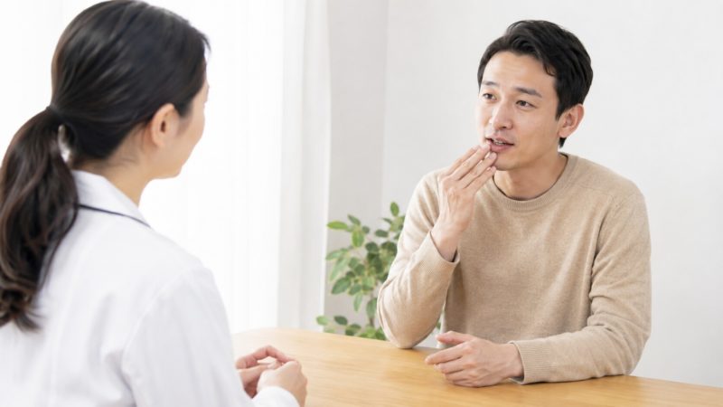 口臭に関するQAを参考にしながら、歯科医師などの専門家に直接相談を行う男性の様子。