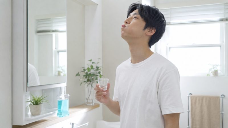 手軽に口内環境を整え、歯の白さを保つサポートをするマウスウォッシュを利用している男性の様子。