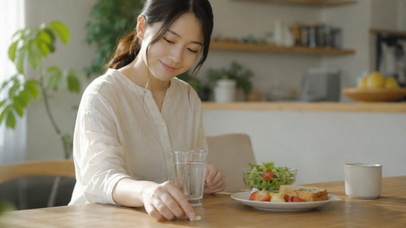 鉄分サプリを忘れないタイミングで飲む習慣。朝食時に水と一緒に摂取する様子。