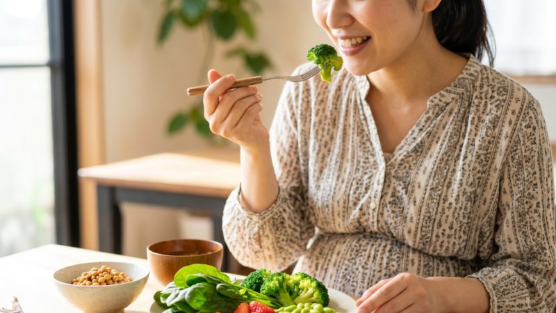 食事から葉酸を摂取する妊婦。皿にはブロッコリーや枝豆、ほうれん草、大豆などの食品が盛られている。