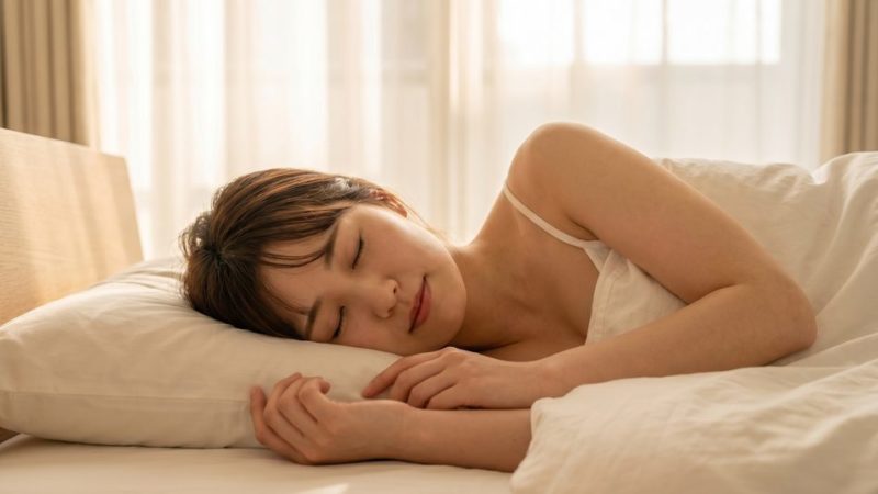 肌荒れ改善や健康的な美肌作りに欠かせない、良質な睡眠をとるためベッドでぐっすり眠る女性。
