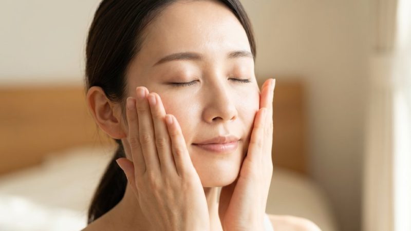 毎日の正しいスキンケアと十分な保湿ケアによって、肌荒れのない潤いのある肌に触れる女性。