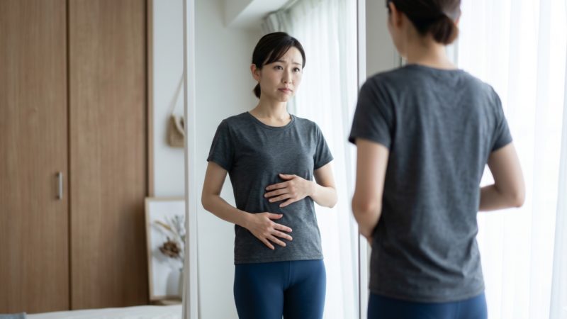 自身の体型や脂肪をチェックし、ダイエットへの意欲を高める女性。サプリメント選びのきっかけとなる場面。